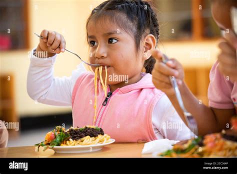 Children eat a nutritious lunch of pasta, vegetables and blood pudding in Sullana Province, Peru ...