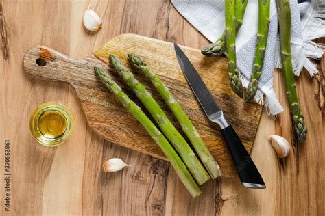 Bunch of raw asparagus stems on wood textured table. Edible Asparagus Officinalis sprouts laid ...