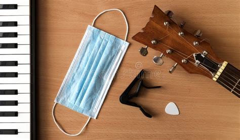 Piano Keys, Acoustic Guitar, Capo, Pick and Blue Medical Mask Lie on a ...