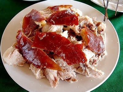 a white plate topped with meat covered in ketchup next to a fork and knife