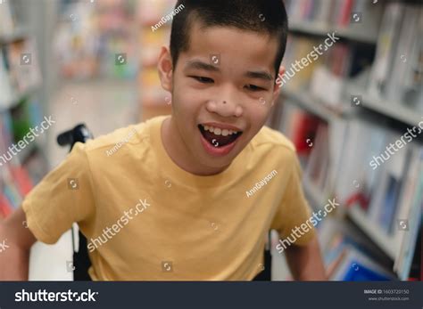 Disabled child on wheelchair having fun choosing books from shelves, Special children's ...