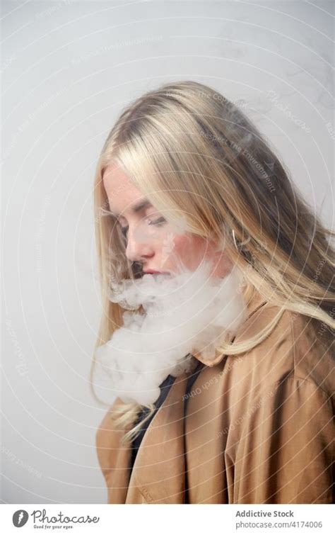 Young woman smoking e cigarette in studio - a Royalty Free Stock Photo ...