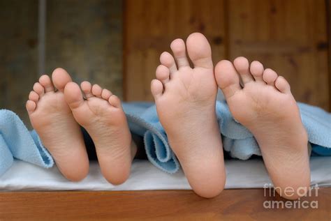 Two children lying in bed focus on feet Photograph by Sami Sarkis