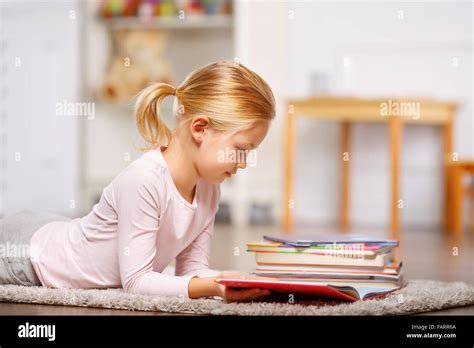 Little girl is lying on the floor and reading Stock Photo - Alamy