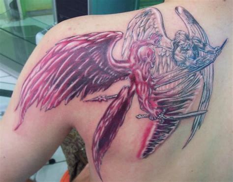 the back of a woman's shoulder with an angel and demon tattoo on it