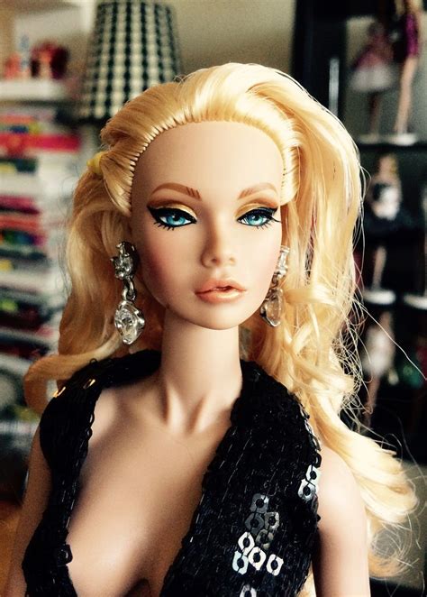 a barbie doll with blonde hair and blue eyes wearing a black dress in a living room