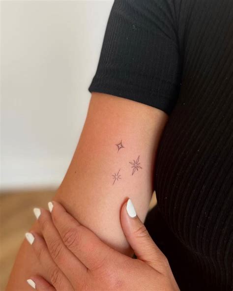 Fine line stars tattooed on the inner arm.