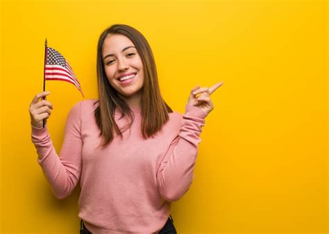 Premium Photo | Young cute woman holding an united states flag pointing to the side with finger