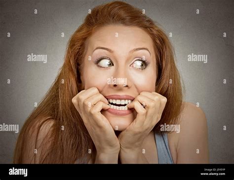 Closeup portrait headshot nervous stressed young woman girl employee student biting fingernails ...