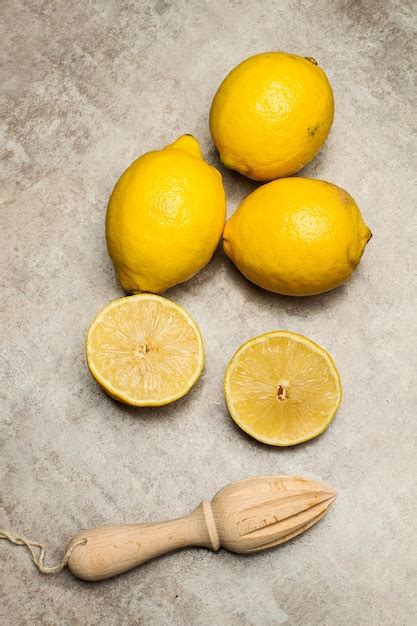 Premium Photo | Lemons and a wooden squeezer on a marble kitchen counter in a top view