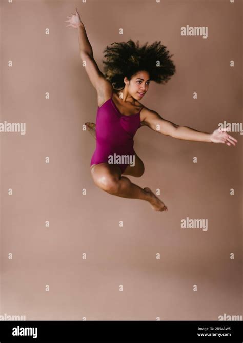 Female dancer with curly hair in leap jump dance pose Stock Photo - Alamy