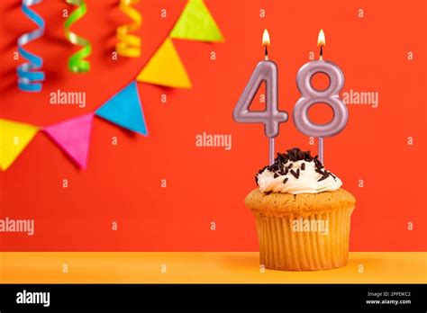 Birthday cake with number 48 candle - Sparkling orange background with ...