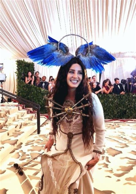 a woman with blue feathers on her head and dress in front of a white tent