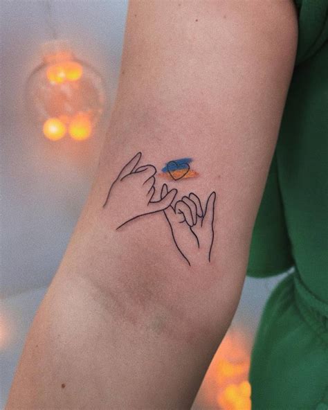 Pinky promise and ukraine flag tattooed on the bicep.