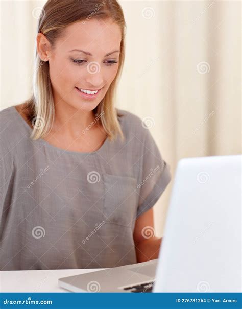 Updating Her Status. a Young Woman Sitting Inside Working on Her Laptop