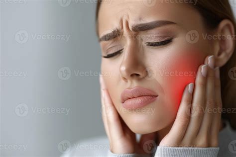 A woman holds her cheek while suffering from a toothache, depicting the