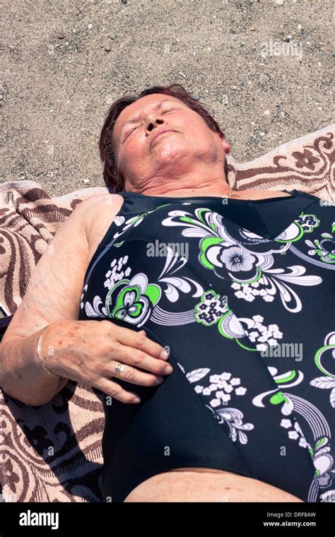 Senior woman sunbathing on the sandy beach Stock Photo - Alamy