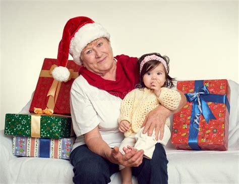 Бабушка и внучка одели в Santa шляпа с подарочными коробками сидит на ...