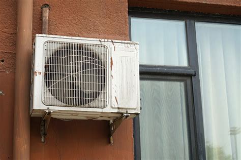 air conditioner installed  rustic house window stock photo