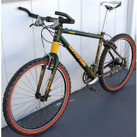 a green and orange bike parked in front of a white building with red rims