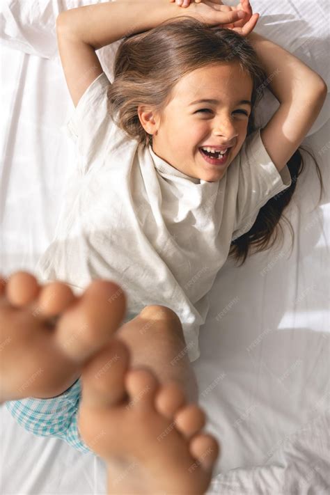 Una linda niña se acuesta en la cama por la mañana y sonríe. | Foto Premium