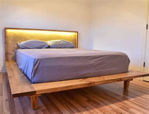 a bed sitting on top of a wooden platform next to a white wall in a bedroom