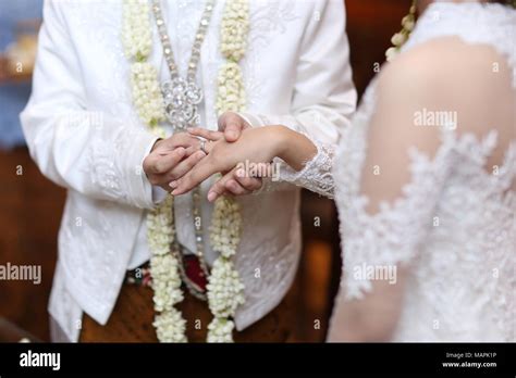 Javanese married couple putting wedding ring in each other's finger ...