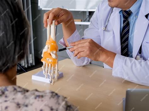 Premium Photo | Closeup pen holding by orthopedic doctor man's hand in white coat pointing to