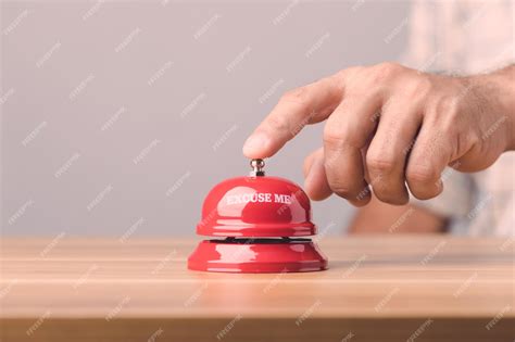 Рука звонит в красный звонок или служебный звонок на коричневом ...