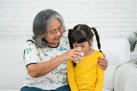 feliz anciana abuela asiática se sienta al lado de su nieta y alimenta