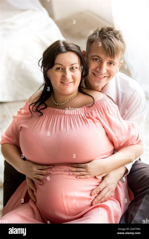 Portrait of handsome man hugging chubby pregnant wife from back Stock