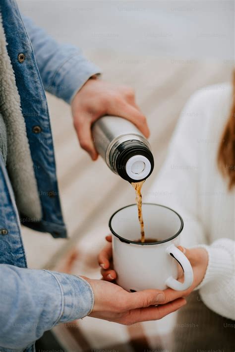 A person pouring a cup of coffee into another person's hand photo – Cup
