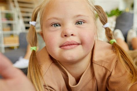 Close up portrait of blonde girl with down syndrome looking at camera