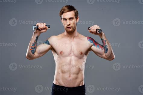 naked athlete with a tattoo and dumbbells in hands phone fitness