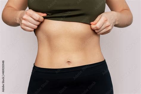 Cropped shot of a young slender woman with toned stomach with abs ...