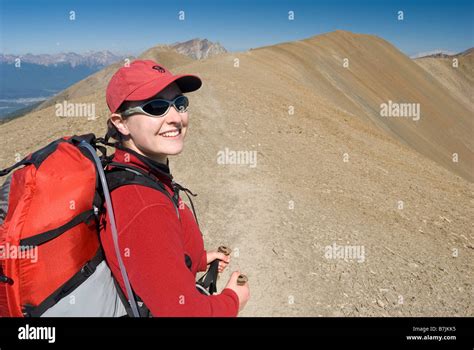 A woman (20-25) smiles while hiking in the alpine; Canada, Alberta ...