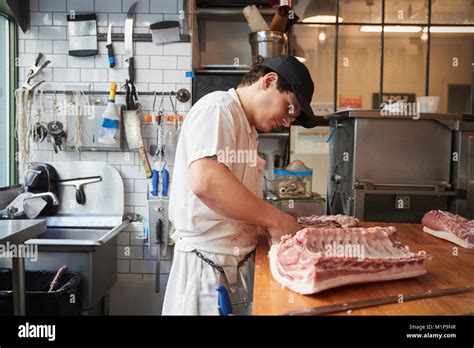 young butcher cutting meat  sell   butchers shop stock photo alamy