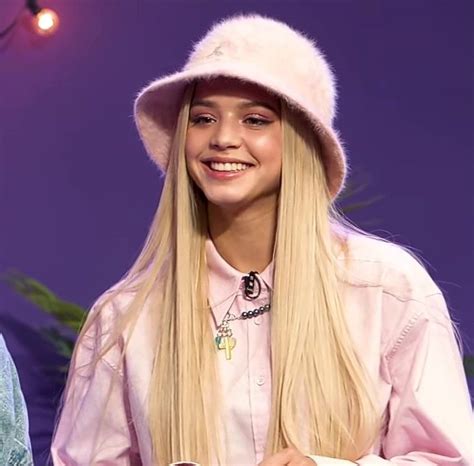 a woman with long blonde hair wearing a white hat and holding a pink ...