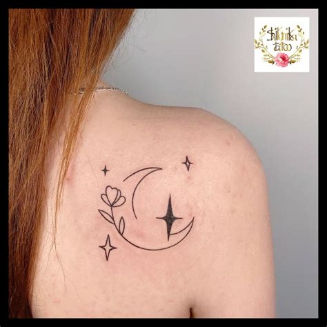 a woman's back shoulder with a crescent moon and stars tattoo on her ...