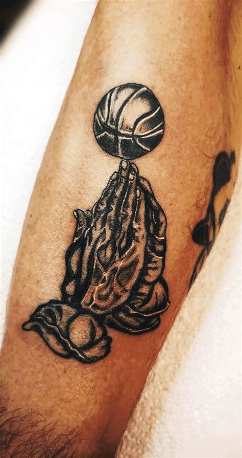 a man with a tattoo on his arm holding a basketball ball and praying to god