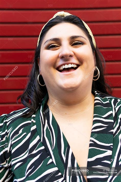 Portrait of cheerful young curvy brunette in stylish striped outfit and