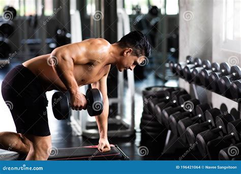 Young Man Naked Bodybuilder Exercising Lifting with Dumbbell at Gym. .Gym Equipment and Sport