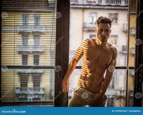 peinzende topless mens  schaduwstrepen van venster stock foto image