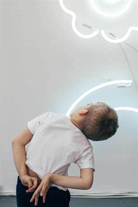 "A Boy Twists His Hands Behind His Back As He Looks Up At LED Tubes On ...