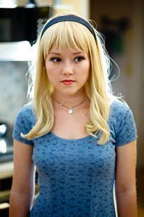 a woman with blonde hair wearing a blue shirt and headband standing in ...