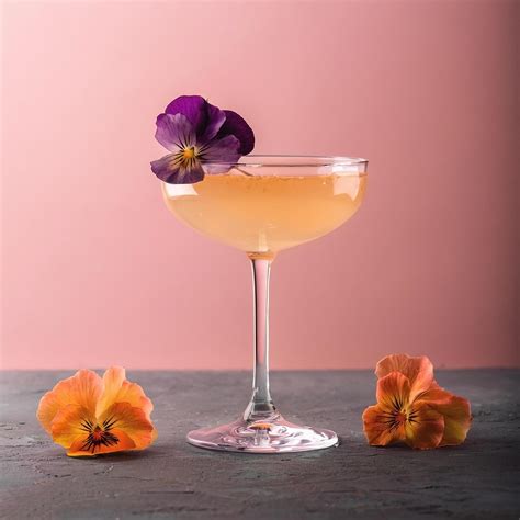 Cocktail with edible flower garnish, on pastel background 51444038