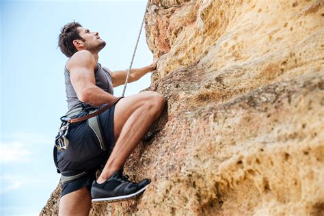 Young man climbing a steep wall in mountain