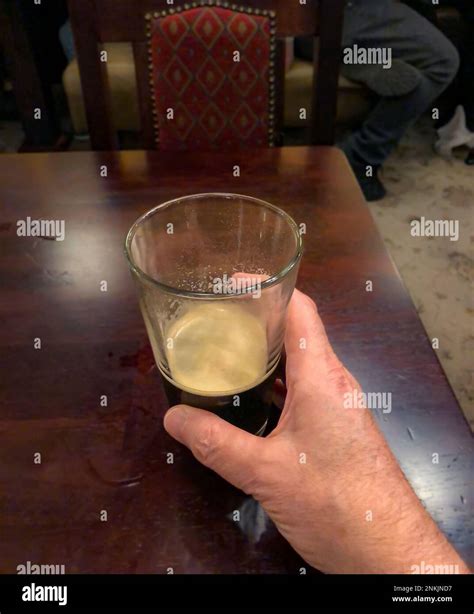 closeup   empty glass  beer  layer  foam  human hand