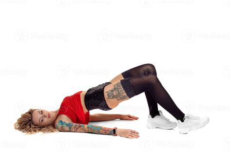 Sexy blond twerk woman with tattoed body and long curly hair is posing