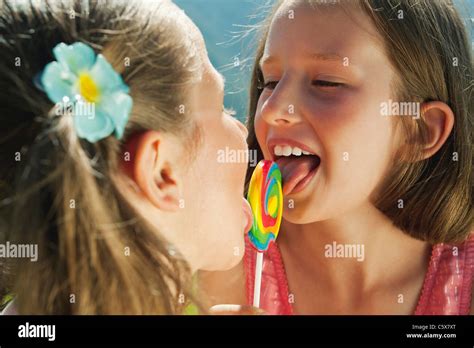 Italy, South Tyrol, Two girls (6-7) (10-11) licking lollypop, portrait